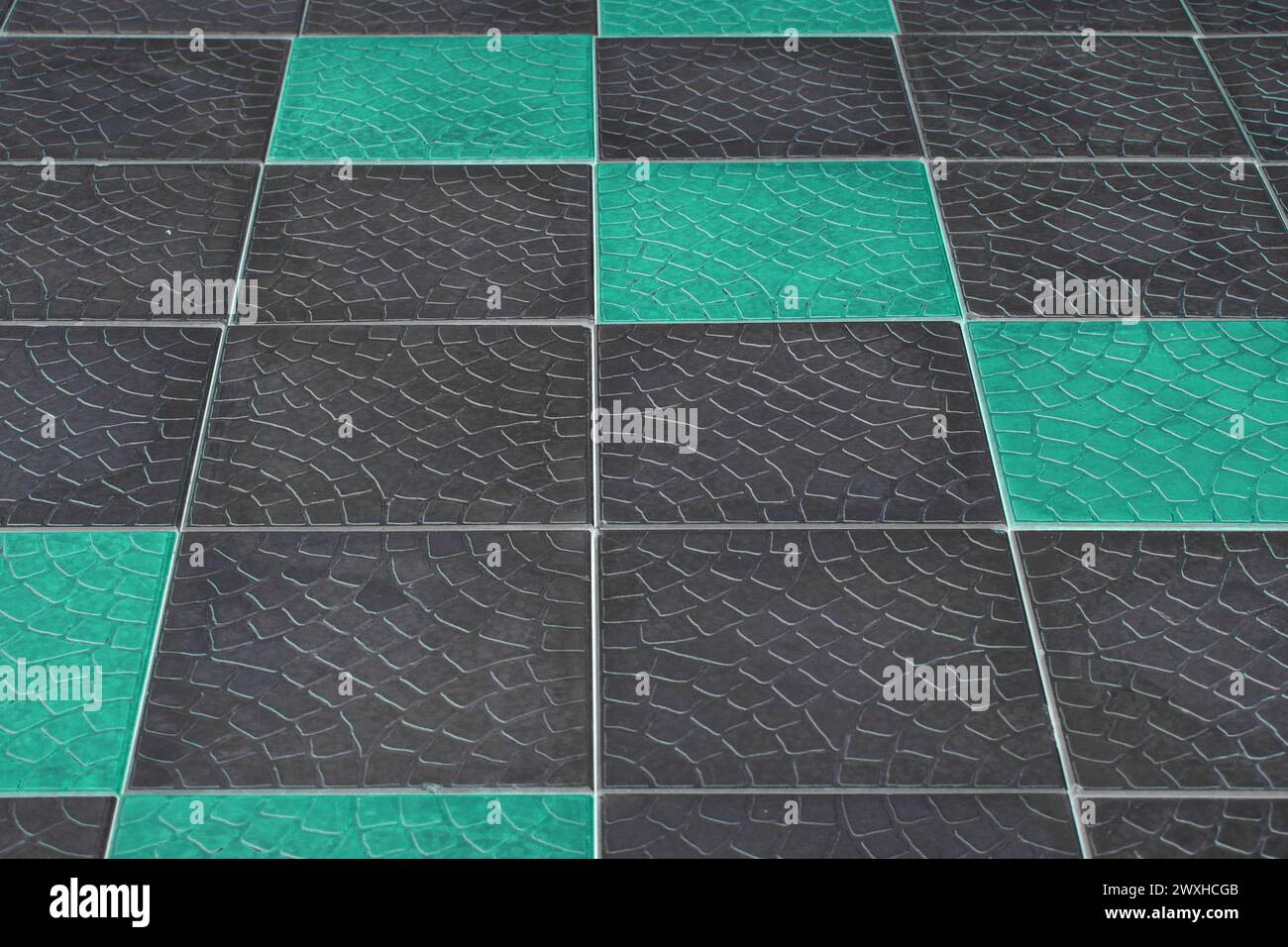 Pavimento in piastrelle di pavimentazione in pietra scura diagonale con motivo nero astratto sfondo urbano con vernice azzurra acquatica. Foto Stock