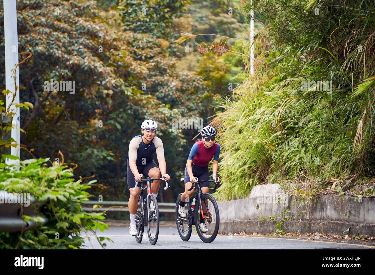 giovani coppie asiatiche ciclisti in bicicletta su strada rurale Foto Stock