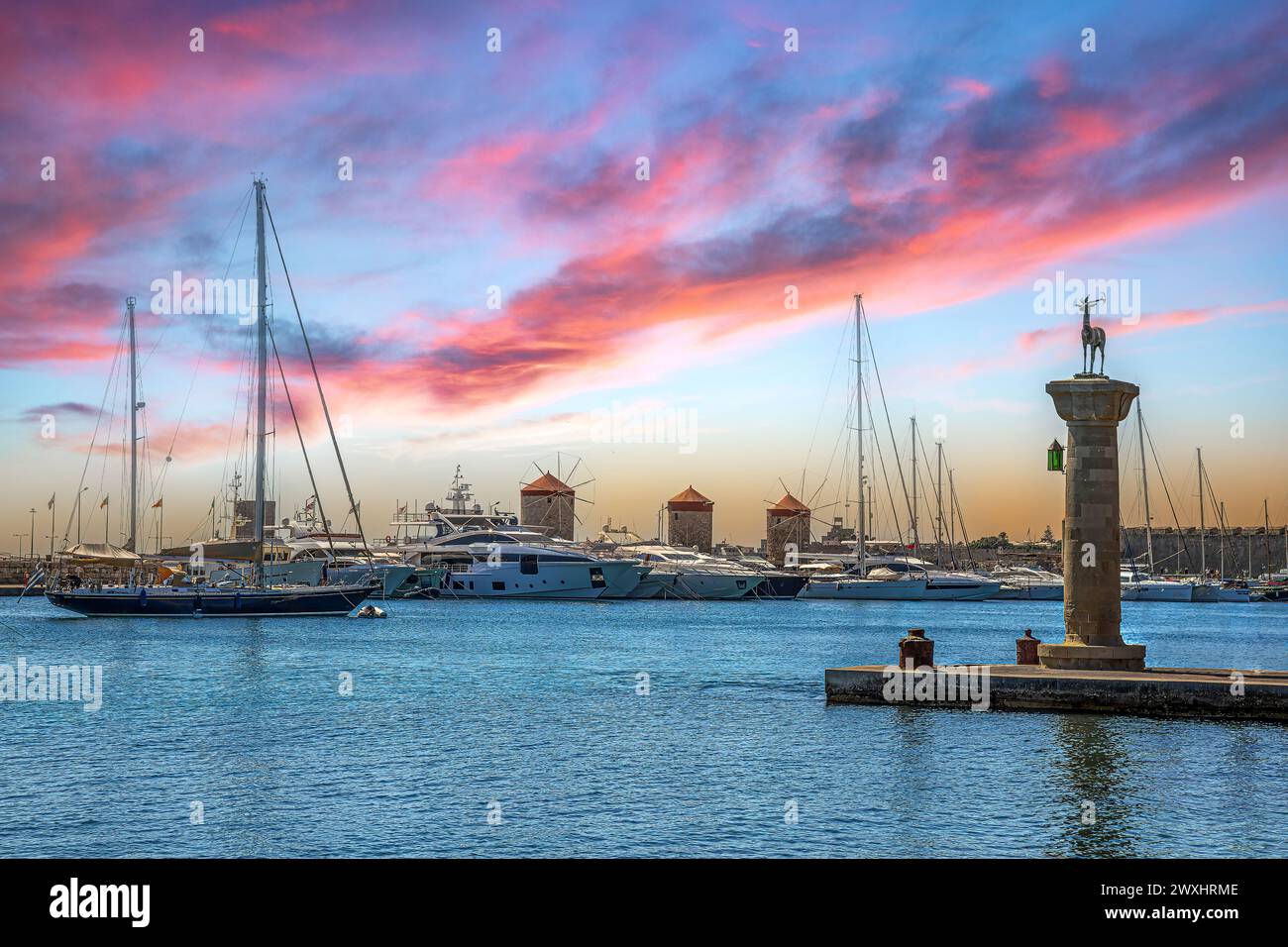 RODI, GRECIA - 29 GIUGNO 2022: Vista pomeridiana con il porto di Mandraki Marina, statue simboliche di cervi dove un tempo sorgeva il colosso di Rodi, Windm Foto Stock