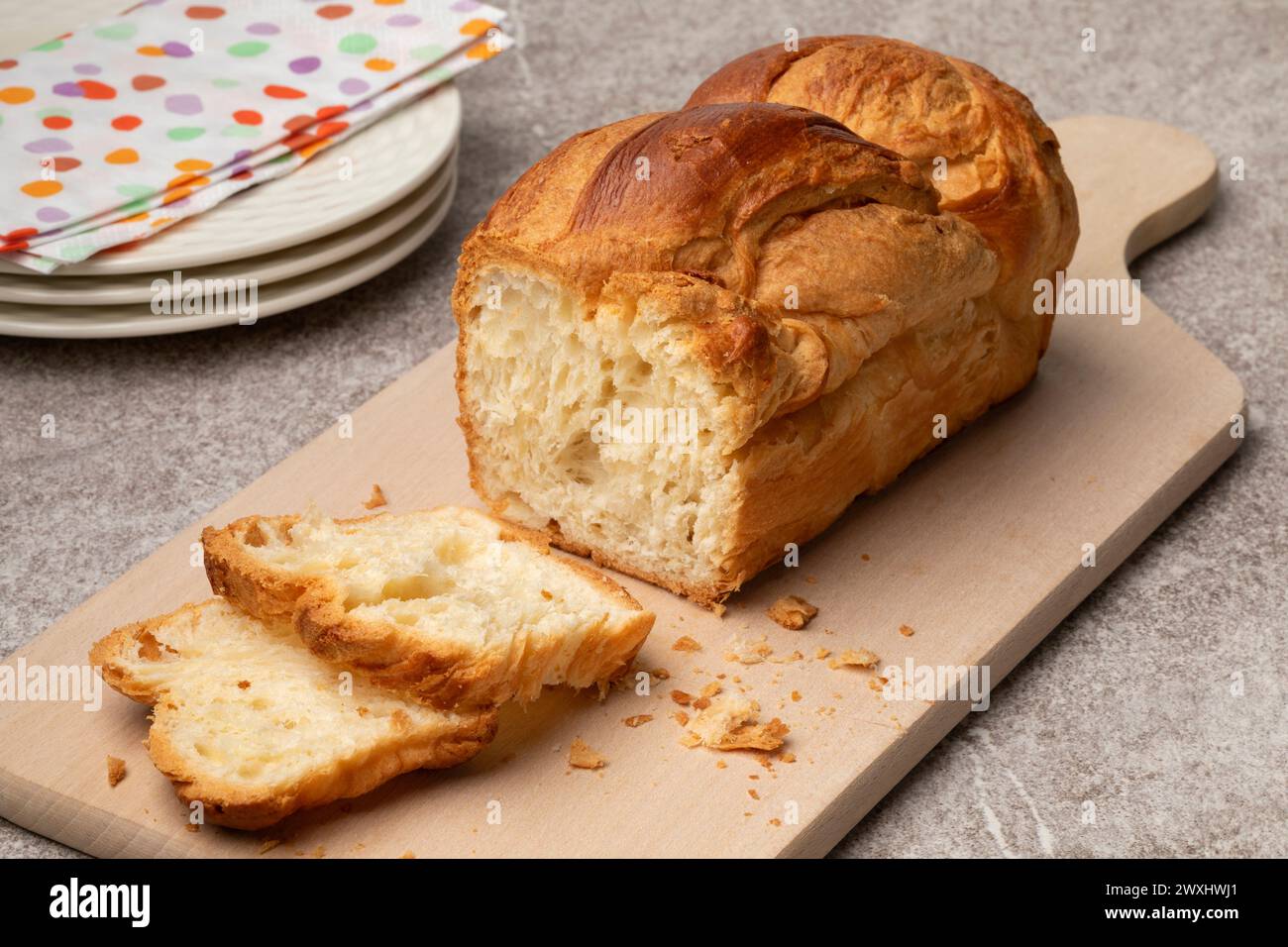 Pane appena sfornato di croissant e fette su un tagliere da vicino Foto Stock