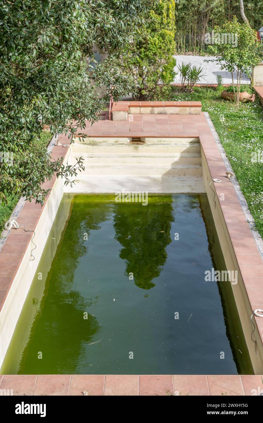 Una piscina ha acqua verde a causa della sporcizia e delle alghe e necessita di manutenzione Foto Stock