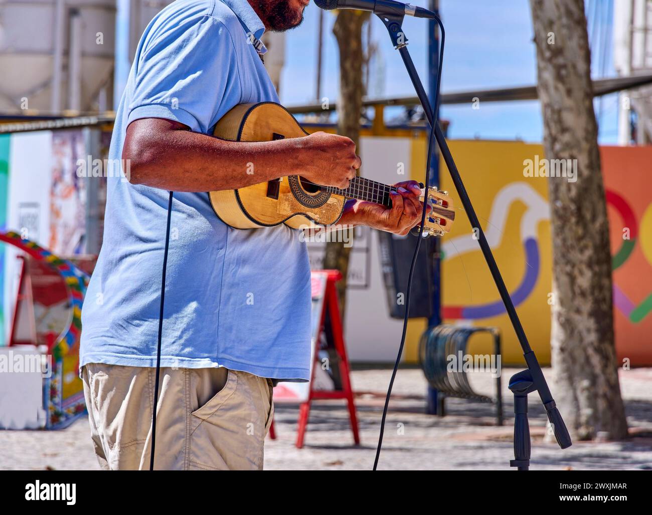 Un musicista suona la chitarra, catturata a metà performance all'aperto. Foto Stock