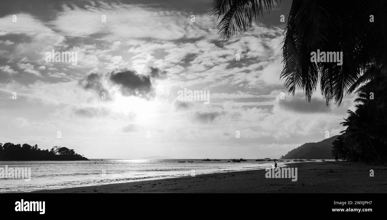 Vista panoramica sulla costa con sabbia bagnata sotto il cielo del tramonto. Foto in bianco e nero. Paesaggio della spiaggia di Cote D'Or, isola di Praslin, Seychelles Foto Stock