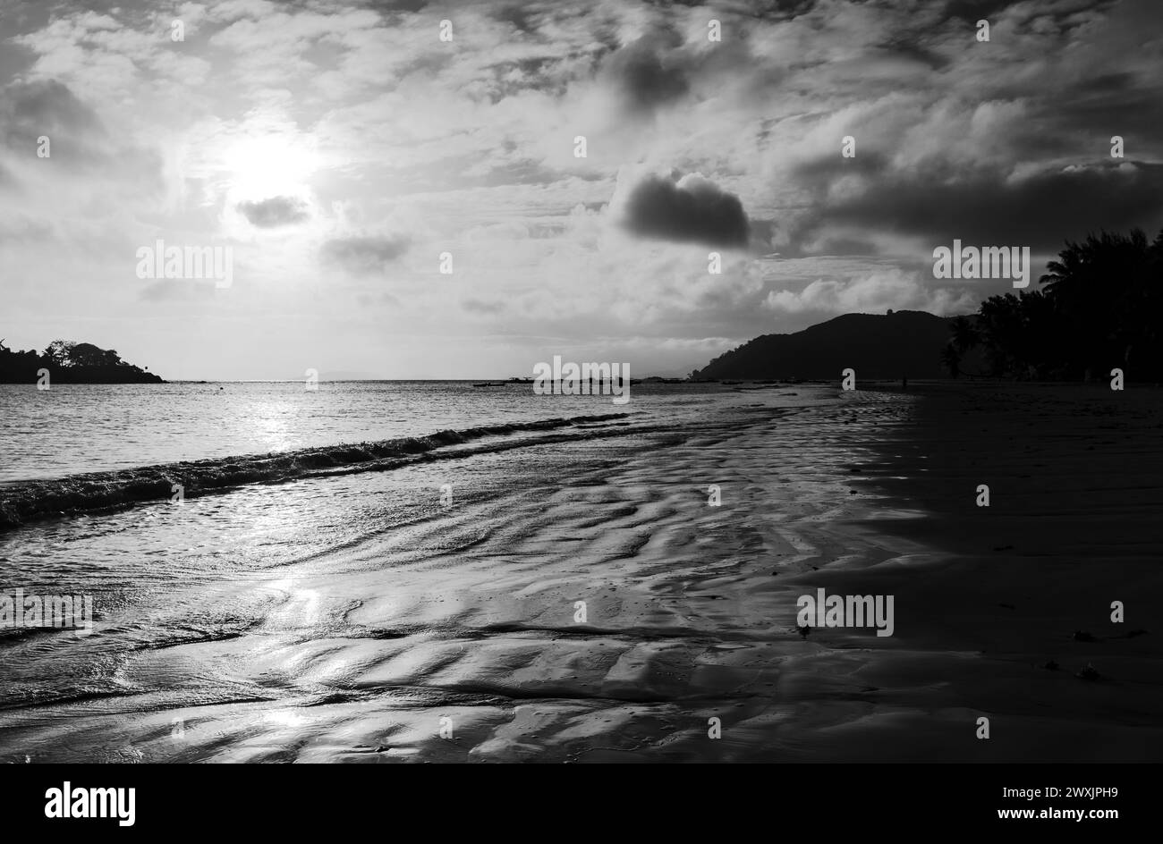 Vista della costa scura con sabbia bagnata sotto il cielo del tramonto. Foto in bianco e nero. Paesaggio della spiaggia di Cote D'Or, isola di Praslin, Seychelles Foto Stock