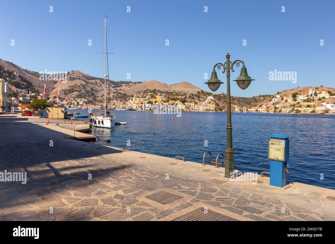 Vista delle case tradizionali colorate e delle barche da pesca nel villaggio di pescatori Symi in una giornata di sole. Grecia. Dodecaneso. Foto Stock