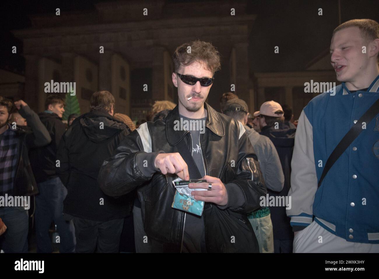 Berlino, dal 31 marzo al 1° aprile 2024 - in un'atmosfera carica di attesa e unità, la porta di Brandeburgo a Berlino emerse come punto focale di un significativo cambiamento sociale nella notte che portò alle prime ore del 1° aprile 2024. Questa storica occasione ha segnato il passo della Germania verso una nuova era nella politica sulle droghe con la parziale legalizzazione della cannabis per uso ricreativo, scatenando una celebrazione collettiva tra la folla riunita. La legge di riferimento, in vigore dal 1° aprile, consente agli adulti tedeschi di possedere e consumare legalmente cannabis, stabilendo limiti di possesso personale fino a 25 gr Foto Stock