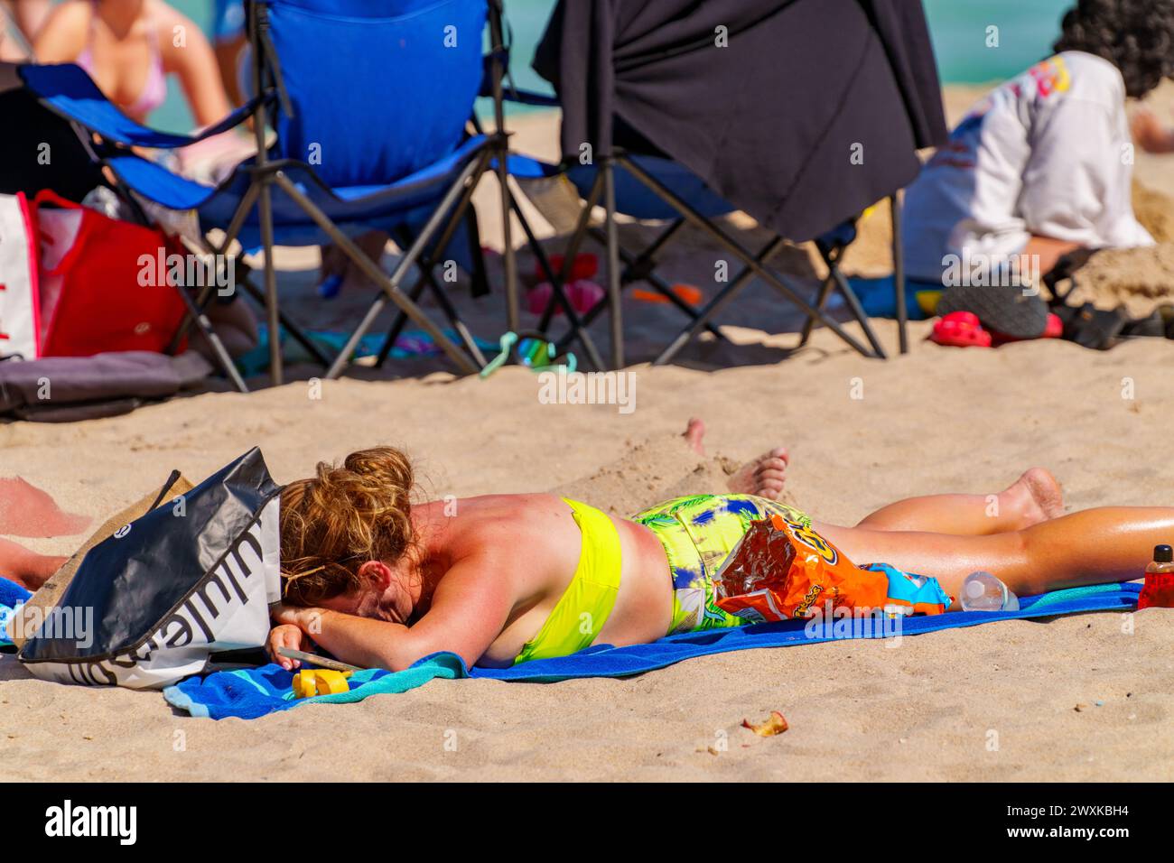 Fort Lauderdale, Florida, Stati Uniti d'America - 30 marzo 2024: Donna adagiata sulla sabbia che viene bruciata al sole Foto Stock