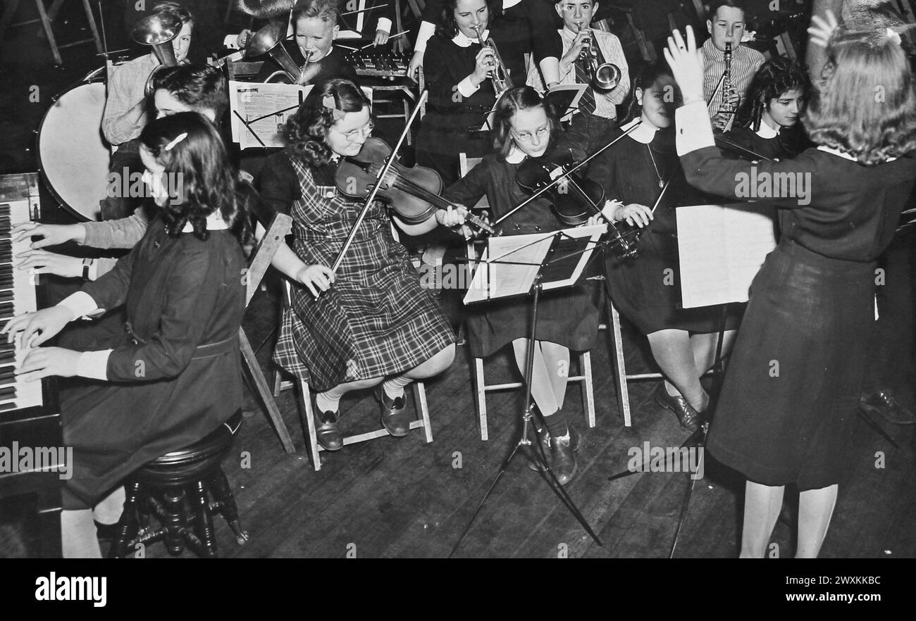 Questa fotografia raffigura una giovane donna che dirige l'orchestra junior a St. Mary's High School di Brookline, Massachusetts, per il National Youth Administration's School Work Program CA. Gennaio 1941 Foto Stock