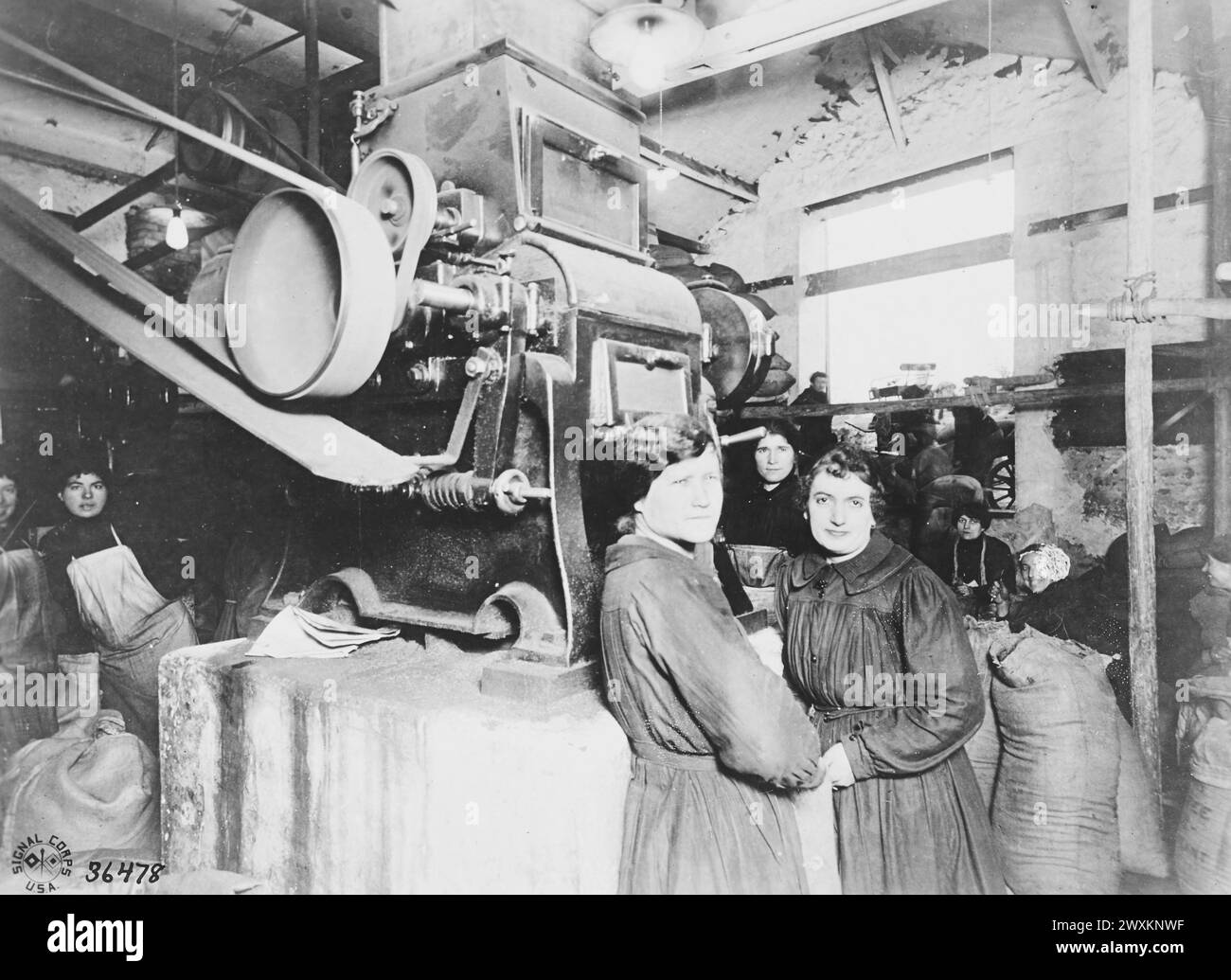 Donne operaie in piedi di fronte a una macchina di macinazione in un impianto di torrefazione del caffè di Essomes, Marna, Francia, CA. 1918 Foto Stock