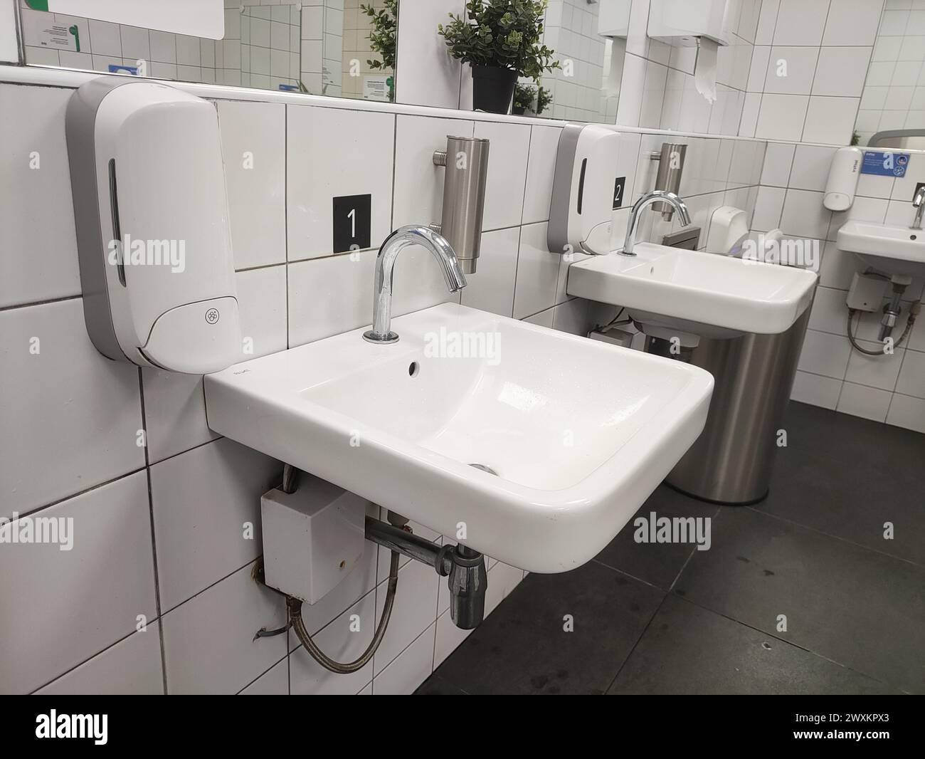 Bagno moderno con lavandino e rubinetto senza contatto nella toilette pubblica e nella toilette. Foto Stock