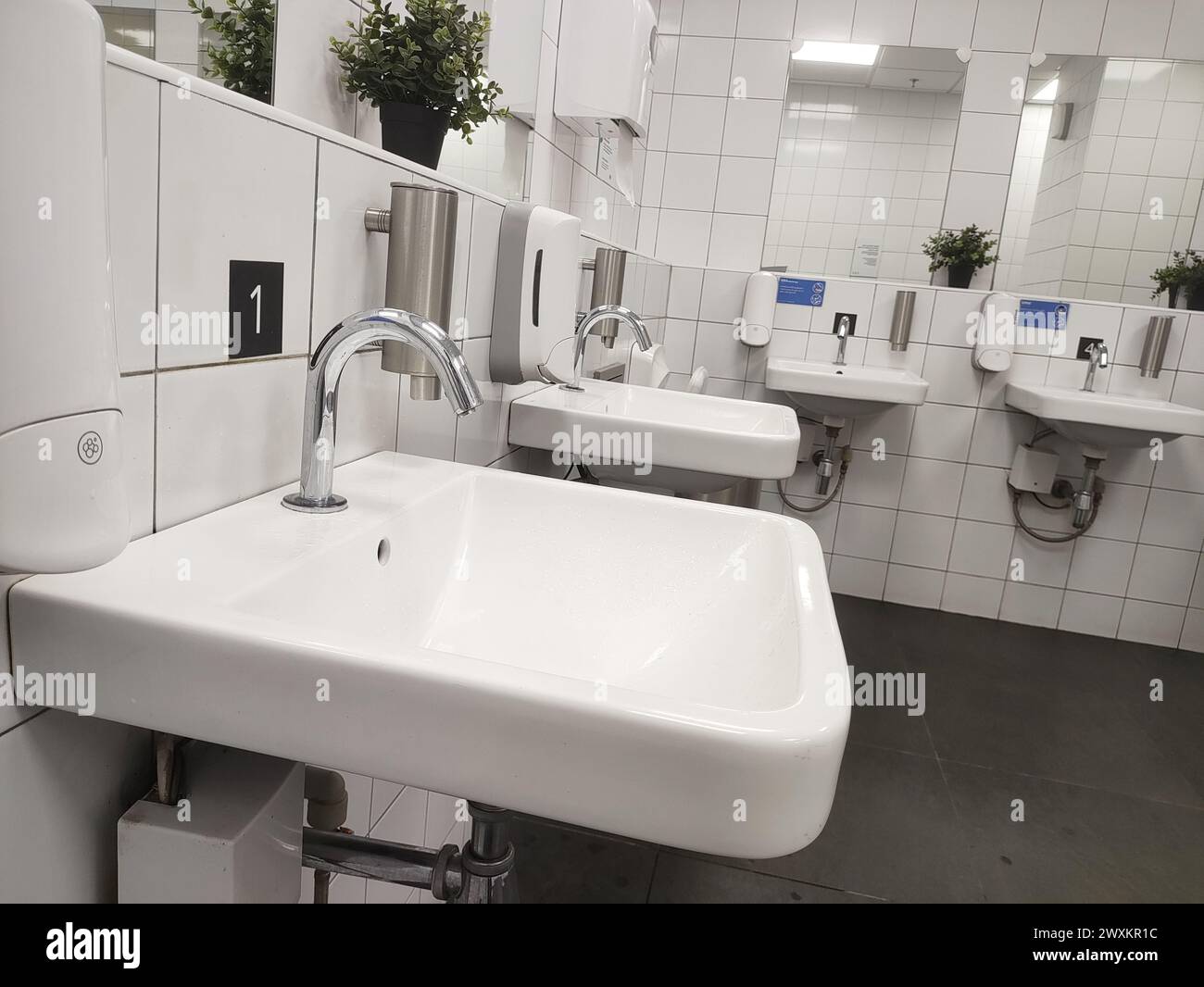 Bagno moderno con lavandino e rubinetto senza contatto nella toilette pubblica e nella toilette. Foto Stock