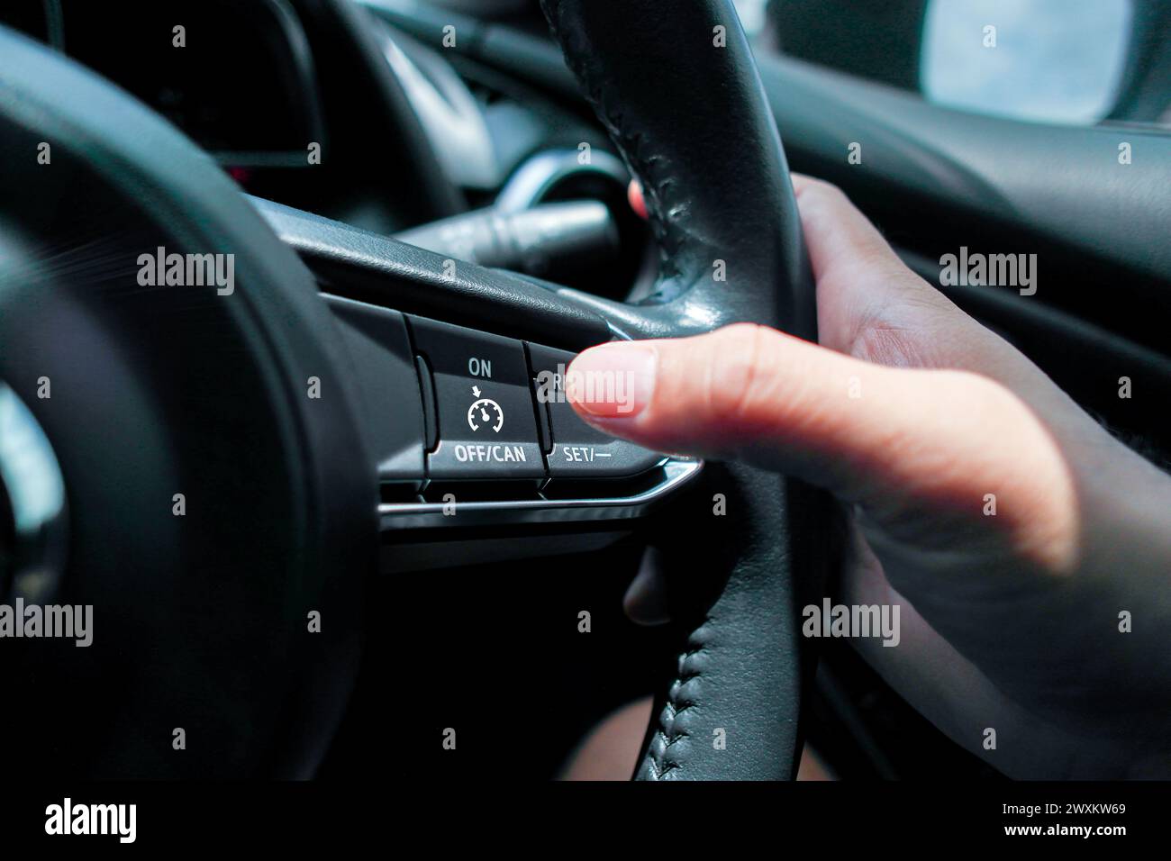 Sistema di controllo della velocità di crociera sul volante di un'auto , pulsante del controllo della velocità di crociera premuto dal conducente , concetto di tecnologia automobilistica Foto Stock