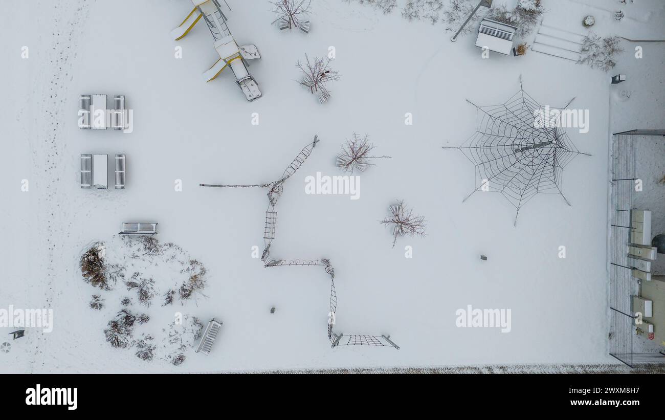 Fotografia con drone del parco giochi per bambini coperto dalla neve durante il giorno nuvoloso d'inverno Foto Stock