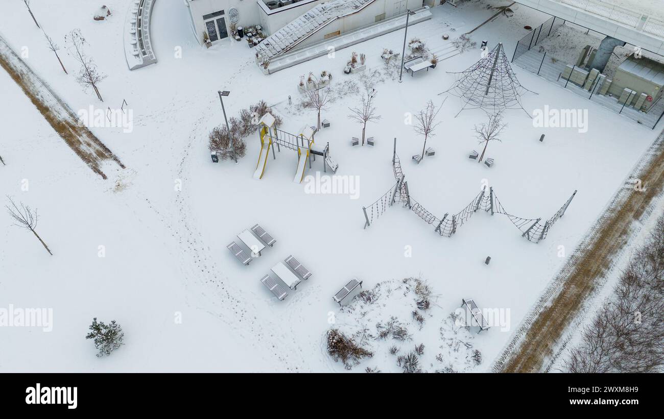 Fotografia con drone del parco giochi per bambini coperto dalla neve durante il giorno nuvoloso d'inverno Foto Stock