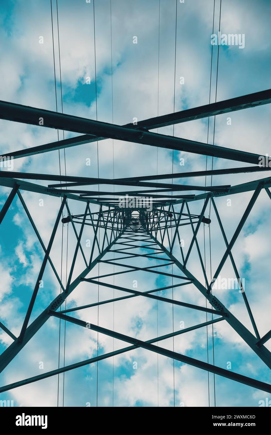 Torre di distribuzione dell'elettricità dal basso, linee elettriche ad alta tensione sotto il cielo nuvoloso. Vista ad angolo basso. Foto Stock