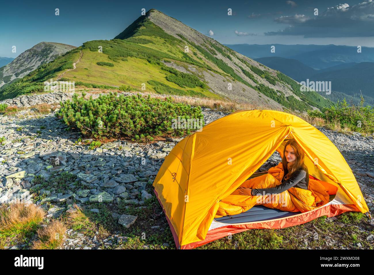 Giovane donna che riposa nella sua tenda in montagna Foto Stock