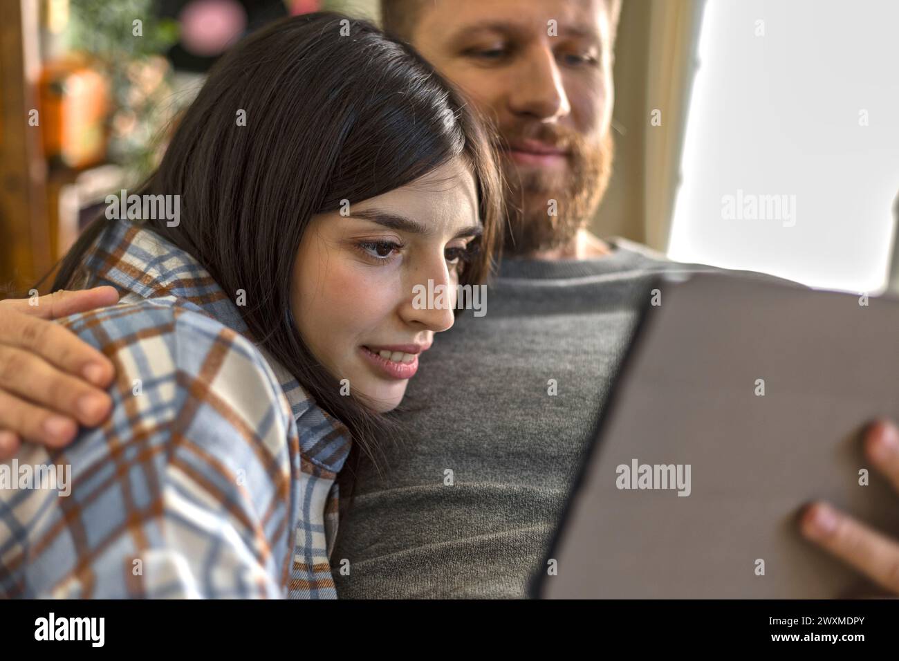 una coppia felice usa il tablet sul divano Foto Stock