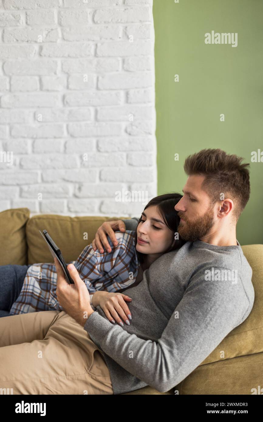 una coppia felice usa il tablet sul divano Foto Stock