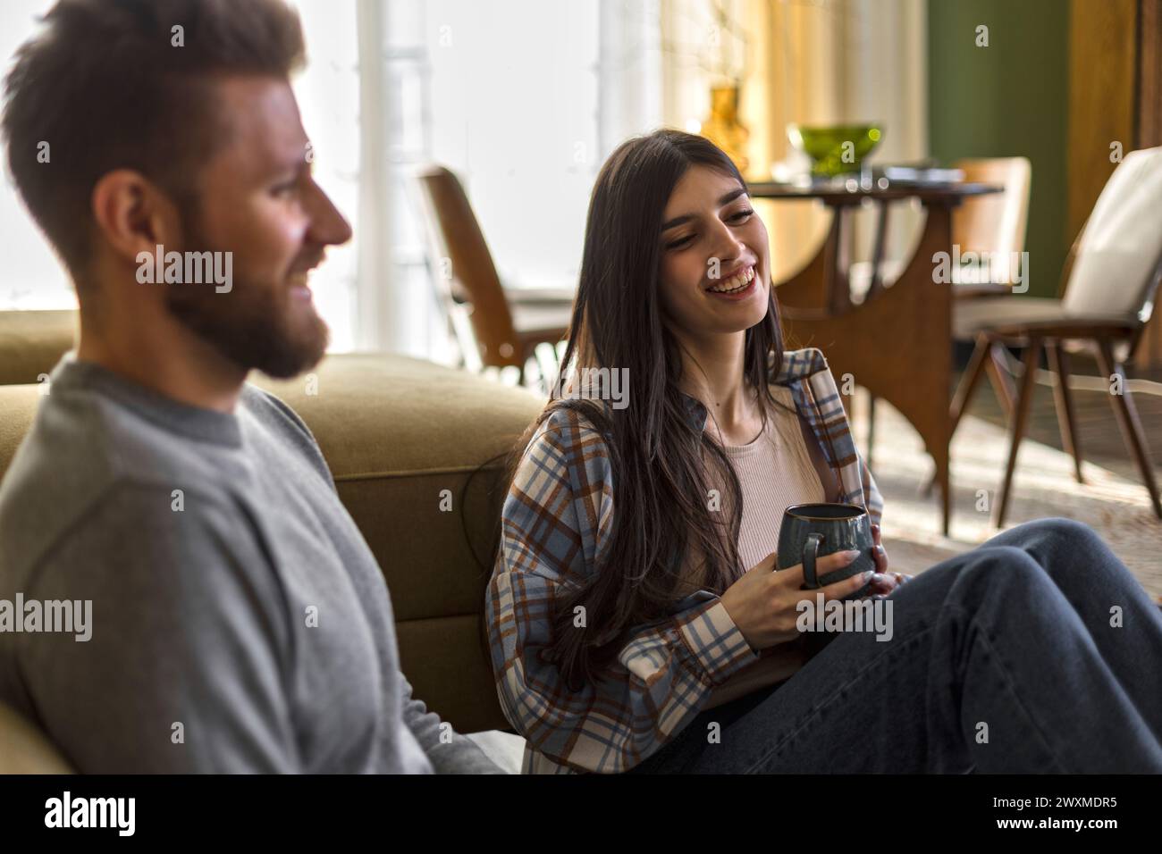 la giovane coppia d'amore siede sul pavimento a chiacchierare, sorridere e ridere gioiosa Foto Stock