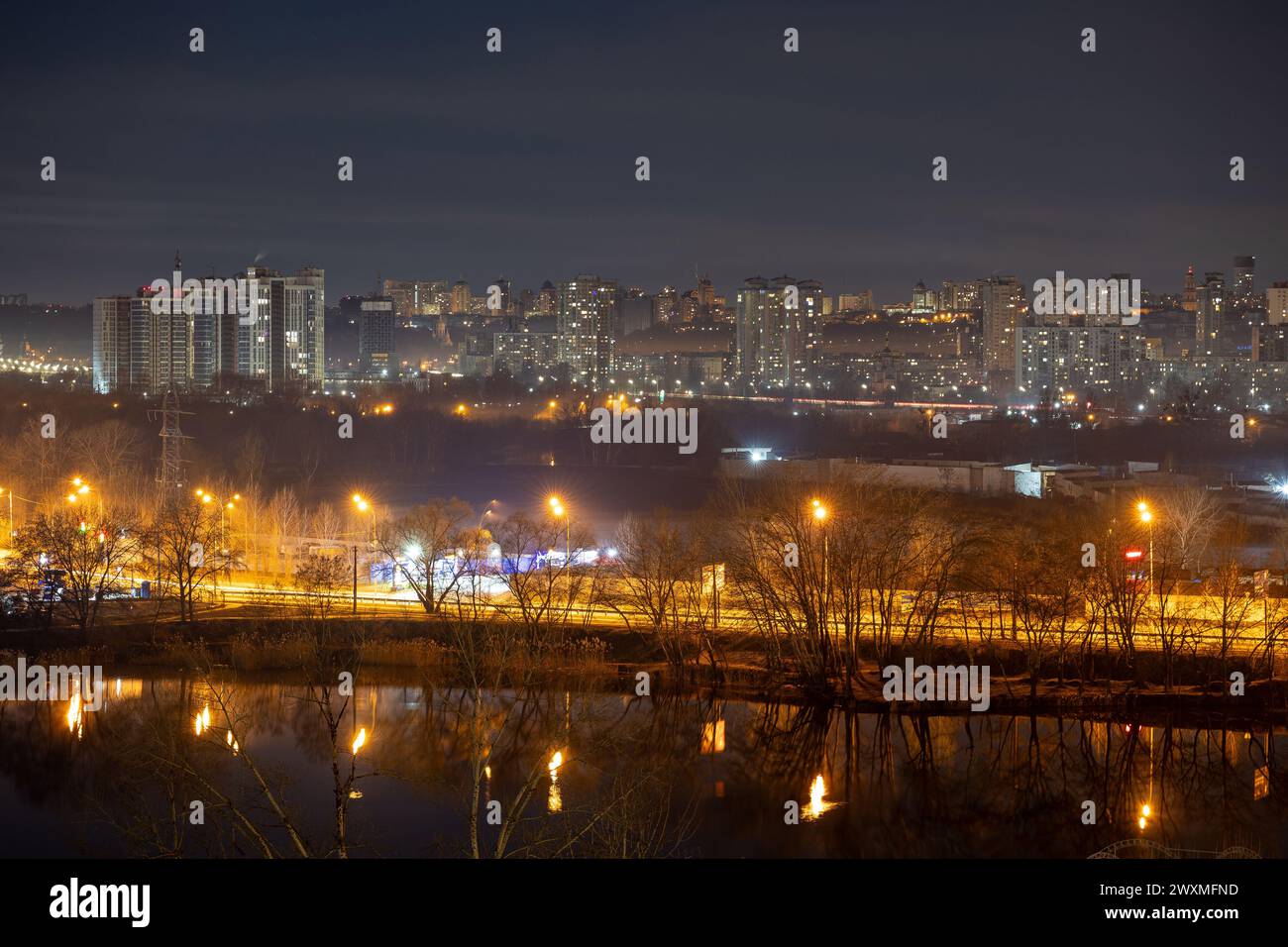 Il paesaggio urbano notturno della grande città. Luce brillante e multicolore sulle strade vuote. Condomini nell'area della città con camera da letto. Kiev alla fine di marzo 2024. Regno Unito Foto Stock