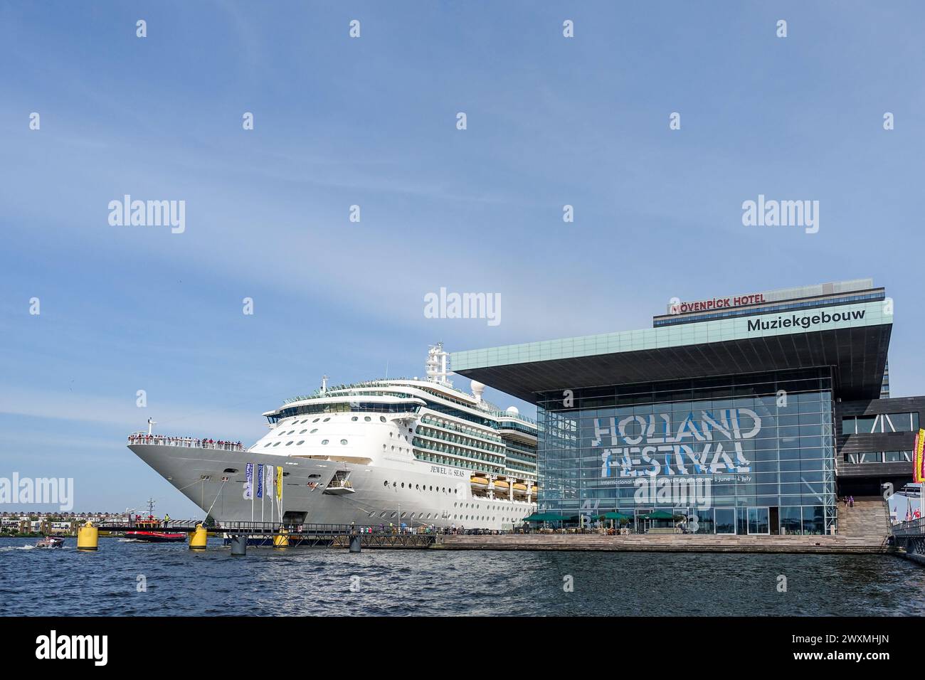 Grande nave da crociera bianca attraccata ad Amsterdam accanto alla moderna sala concerti di vetro Bimhuis durante l'Holland Festival Foto Stock