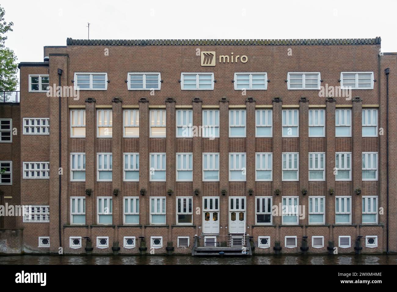 Facciata dell'edificio per uffici Miro con architettura simmetrica in mattoni e ingresso sul canale ad Amsterdam, Paesi Bassi Foto Stock