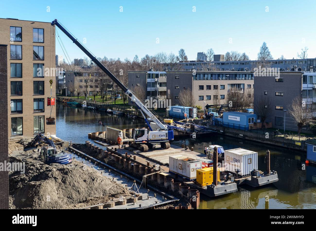 Sito di costruzione di canali urbani ad Amsterdam Est, con gru, attrezzature e piattaforma sospesa circondata da edifici residenziali Foto Stock