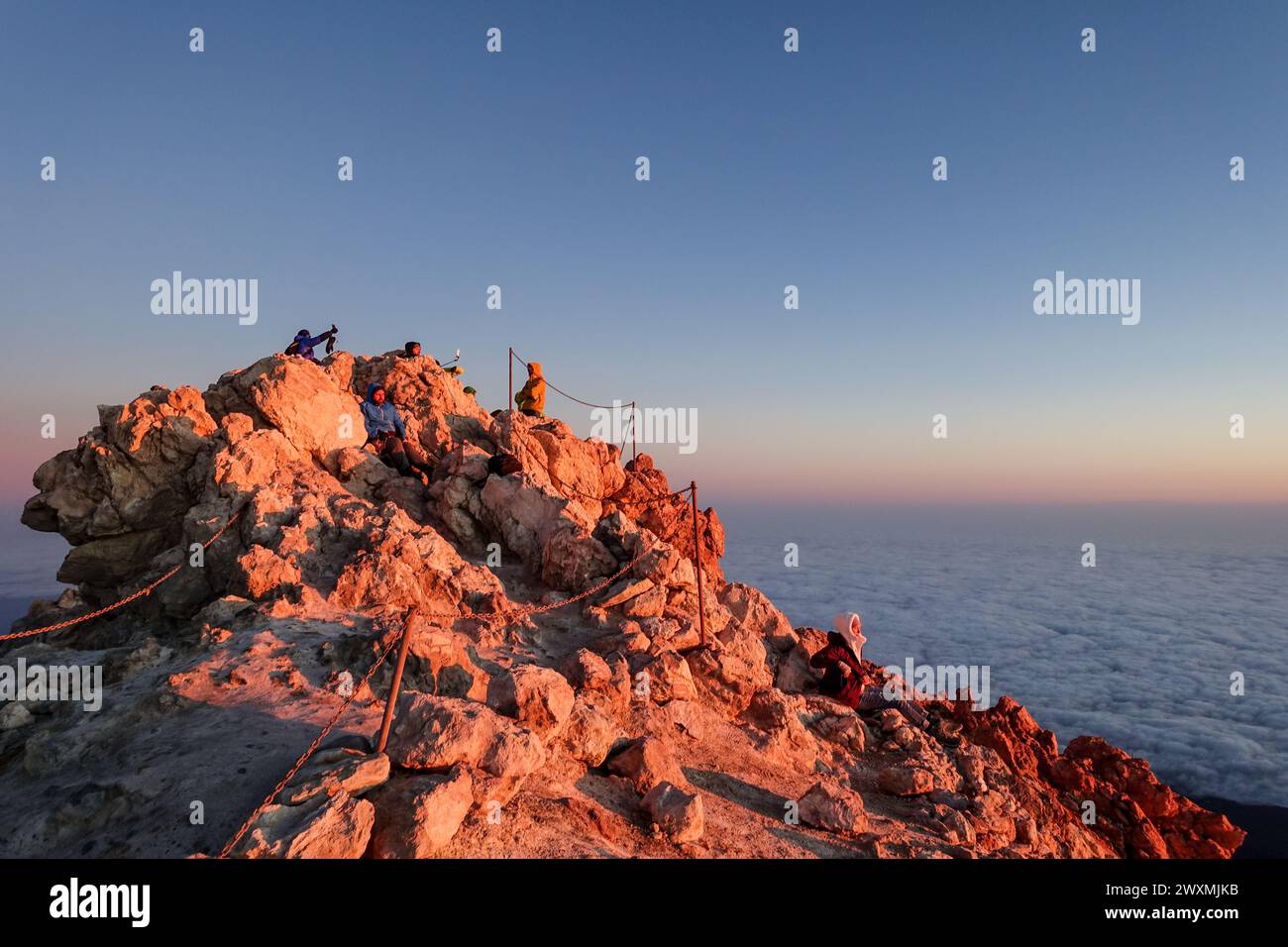 Gli escursionisti raggiungono la vetta del monte Teide all'alba con un mare di nuvole sotto e un cielo limpido sopra Foto Stock