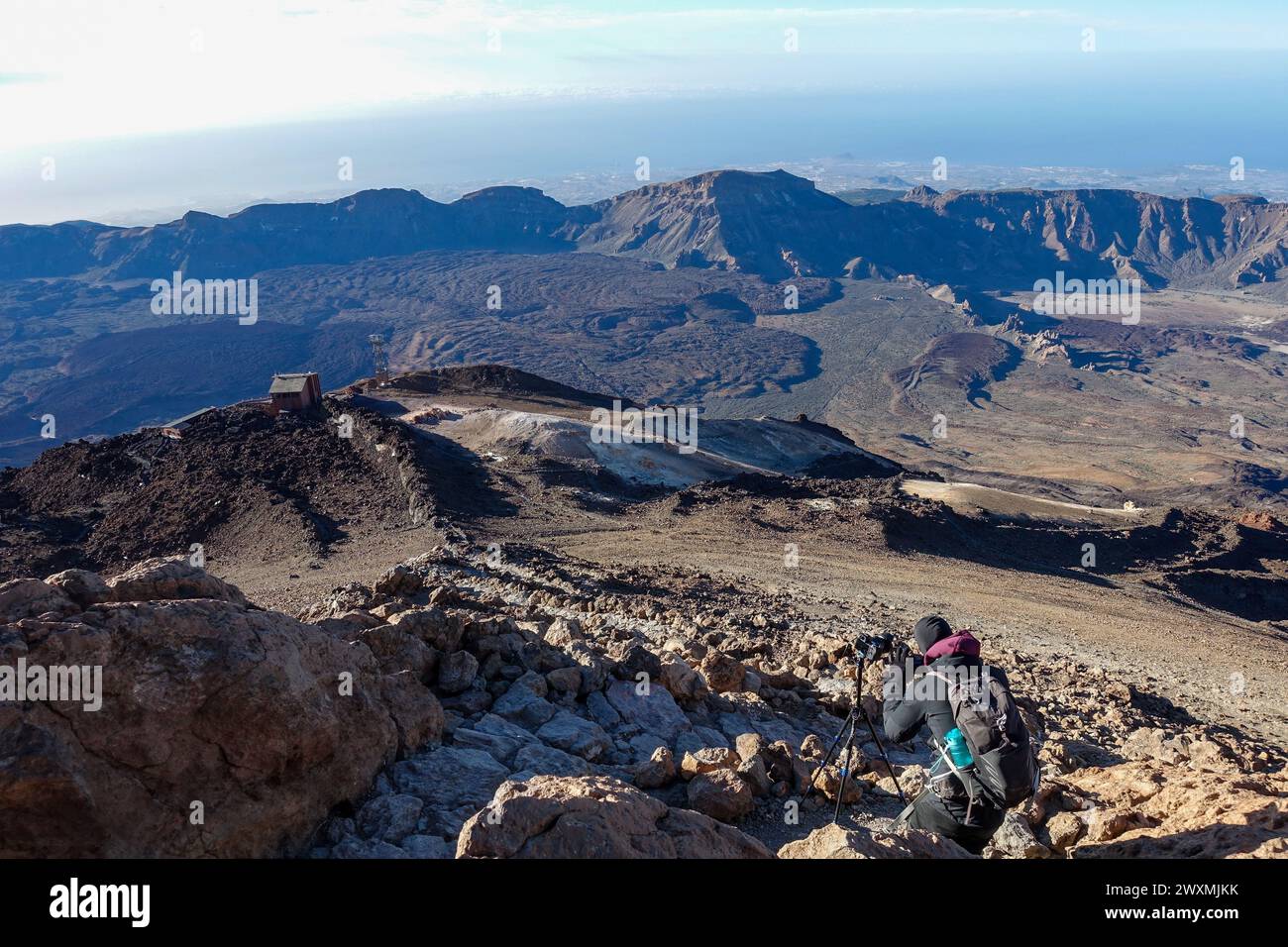 Fotografo con zaino e treppiede che cattura il paesaggio roccioso delle montagne vulcaniche da un punto panoramico ad alta quota sul monte Teide, Tenerife Foto Stock