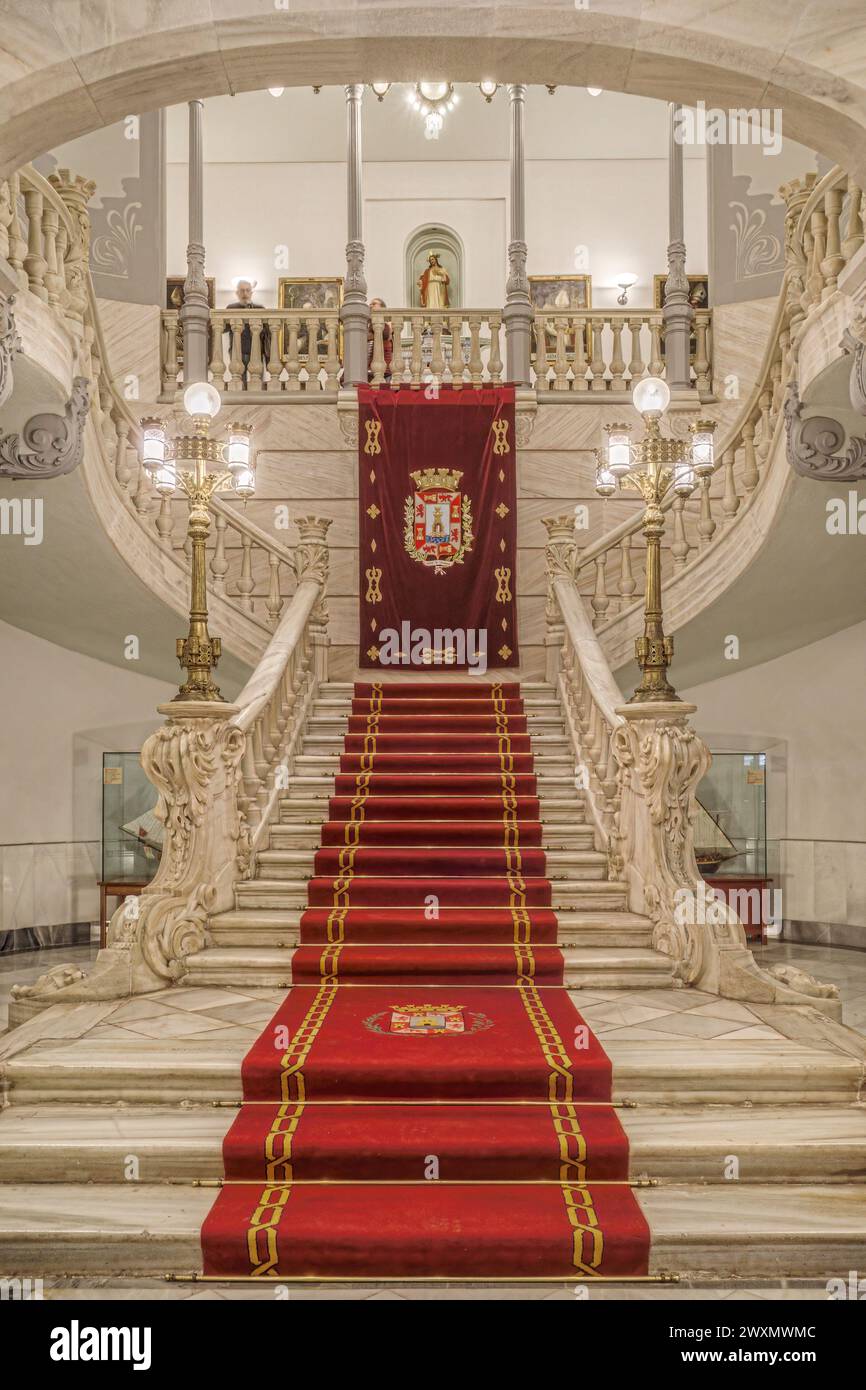 Scala imperiale del Municipio con opere in fusione di colonne e lampade, tappeto rosso e stemma della città di Cartagena, regione di Murcia. Foto Stock
