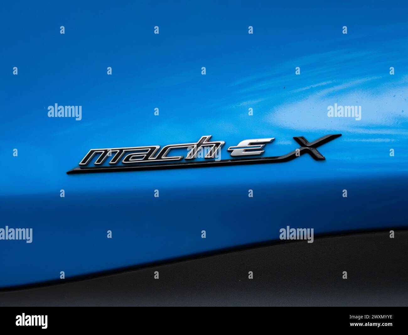 Simbolo Ford Mach-e sull'esterno di un'auto elettrica blu. Logo con le lettere come parte del modello e del marchio automobilistico. Foto Stock