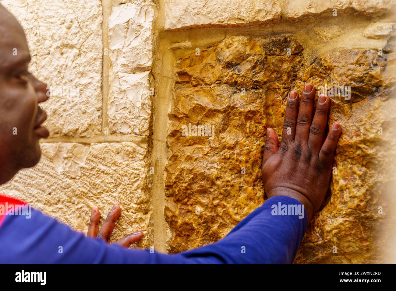 Gerusalemme, Israele - 29 marzo 2024: Scena occidentale del venerdì Santo in via dolorosa, con il pellegrino che mette la mano nell'impronta della stazione V. Vecchia città di Jer Foto Stock