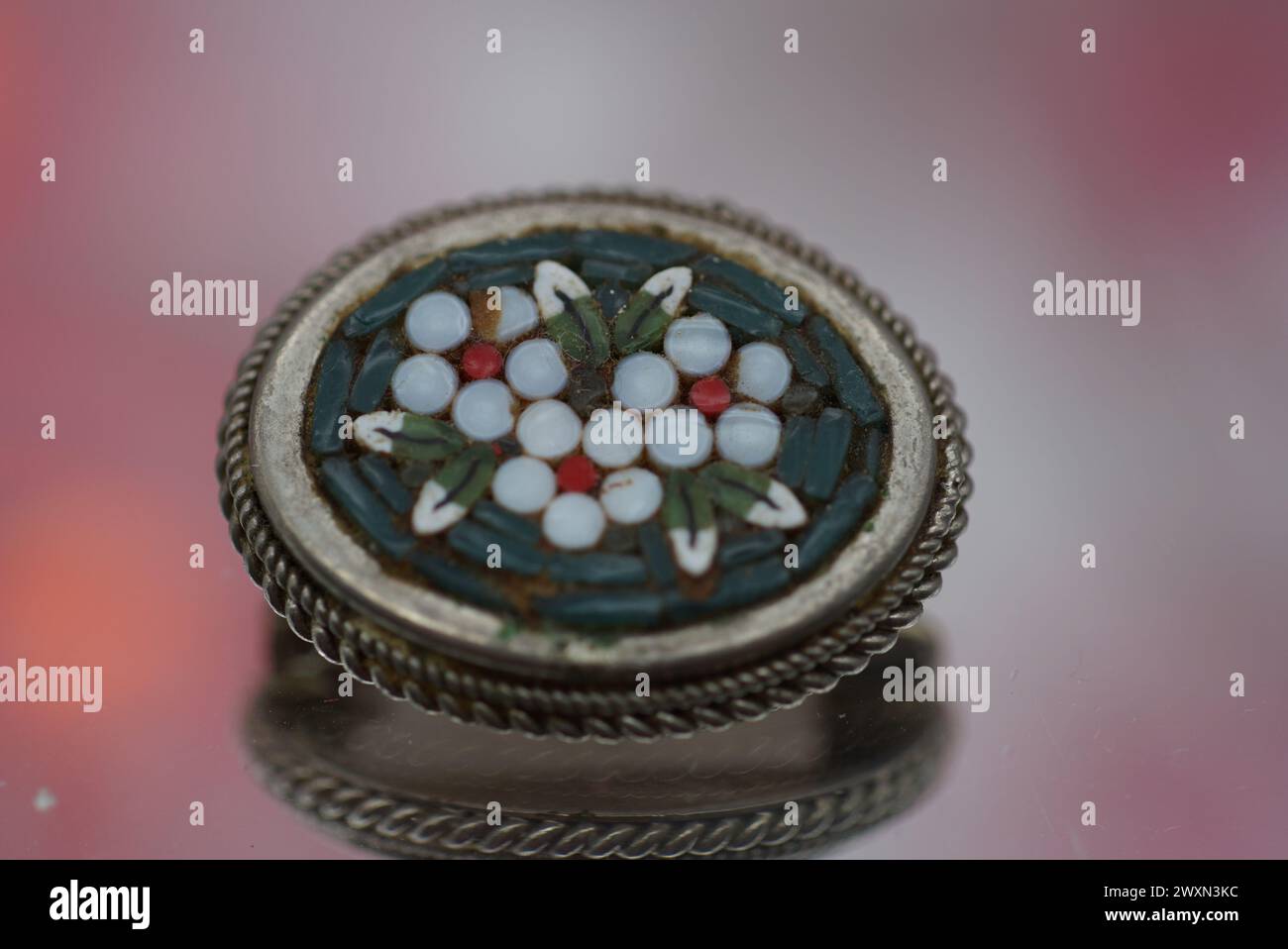 Un trinket in vetro sulla superficie rosa, decorato con ciottoli bianchi Foto Stock