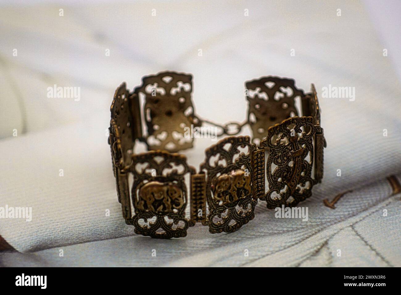 Un bracciale si appoggia su un tovagliolo con due piccole fioriture Foto Stock