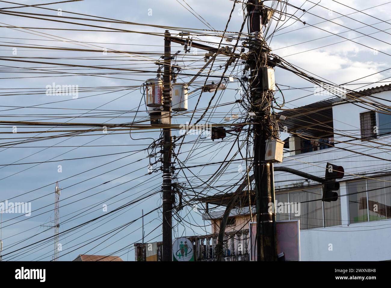 un intreccio di cavi elettrici incornicia un polo urbano, mostrando la complessa e caotica infrastruttura energetica della città Foto Stock