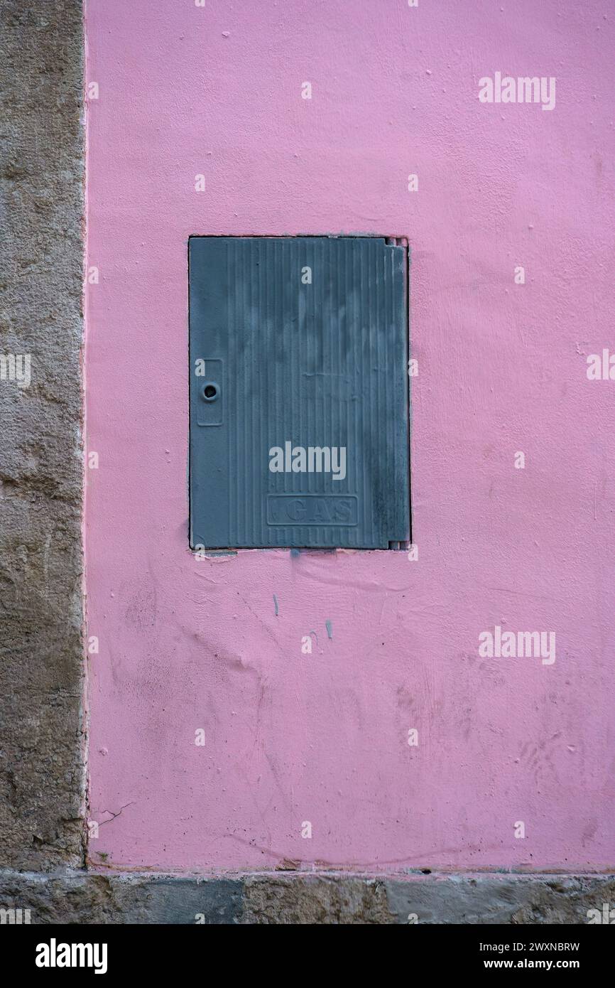 Piccola porta metallica blu su una vivace parete in cemento rosa Foto Stock