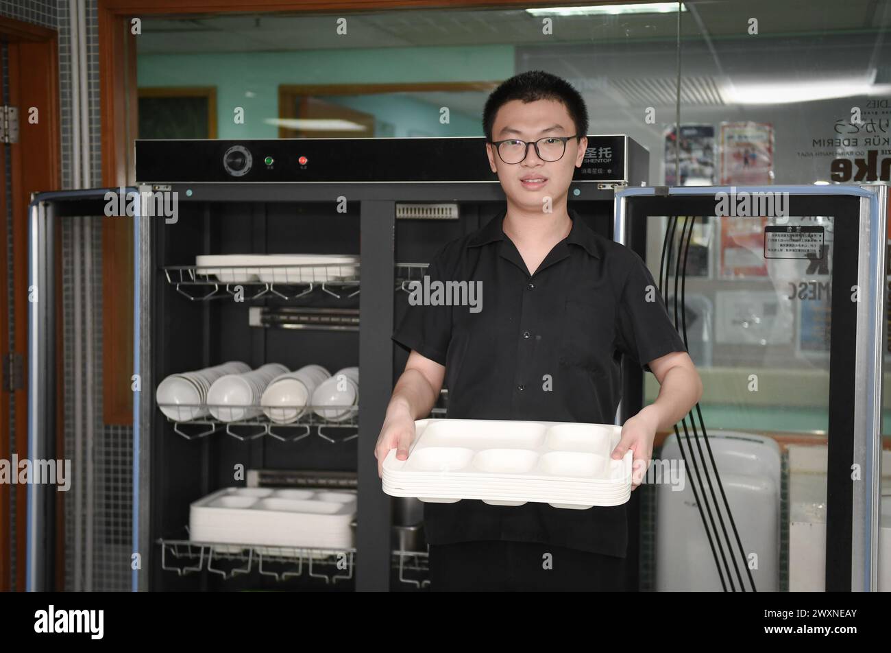 (240401) -- SHENZHEN, 1° aprile 2024 (Xinhua) -- il giovane autistico Guan Hao posa per una foto nella sala da pranzo di un hotel a Shenzhen, nella provincia del Guangdong della Cina meridionale, 27 marzo 2024. Guan Hao, 23 anni, si è Unito all'hotel nel giugno 2021 come cameriere della sala da pranzo del personale. Come altri dipendenti, ora lavora otto ore al giorno ed è responsabile di posizionare piatti puliti, pulire la spazzatura e la sala. Agli occhi dei suoi leader e colleghi, Guan è ora un buon dipendente. Questo martedì segna la diciassettesima giornata mondiale della consapevolezza dell'autismo. Nella Shenzhen del sud della Cina, alcuni giovani autistici, che erano chiamati 'ch Foto Stock