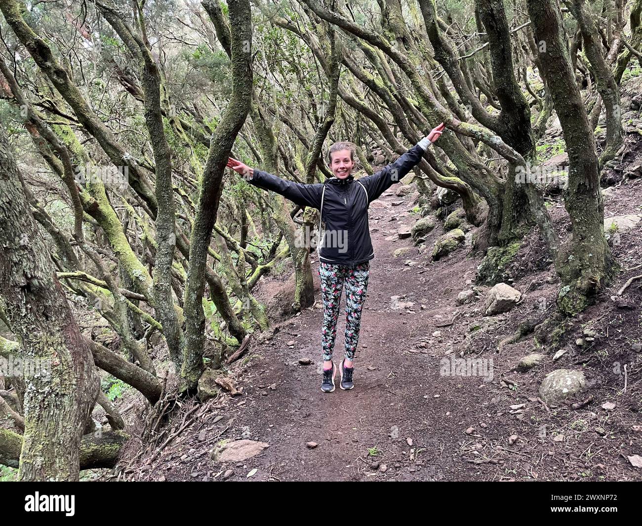 Una persona si trova su un sentiero nella foresta, mettendosi in posa per la macchina fotografica Foto Stock