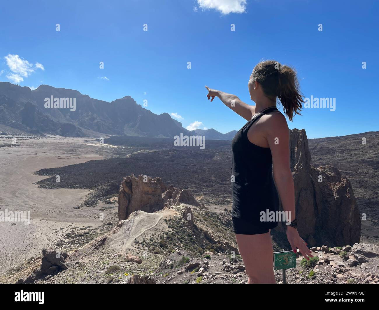 Un escursionista che punta verso il cielo sulla cima di una montagna Foto Stock