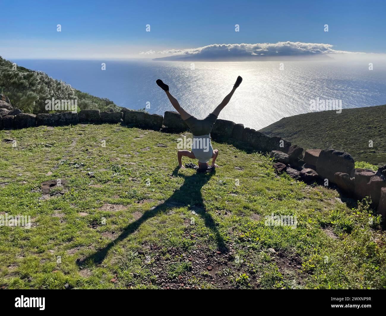 Persona che pratica il supporto per le mani su un pendio roccioso vicino al corpo idrico Foto Stock