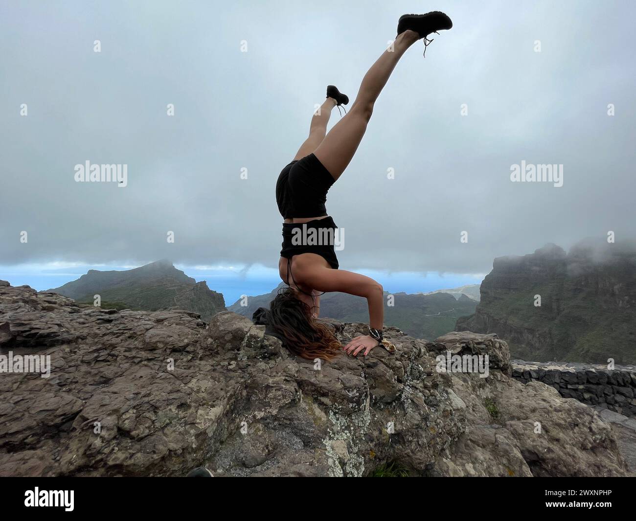 Una donna in equilibrio in un palco in cima a una roccia Foto Stock