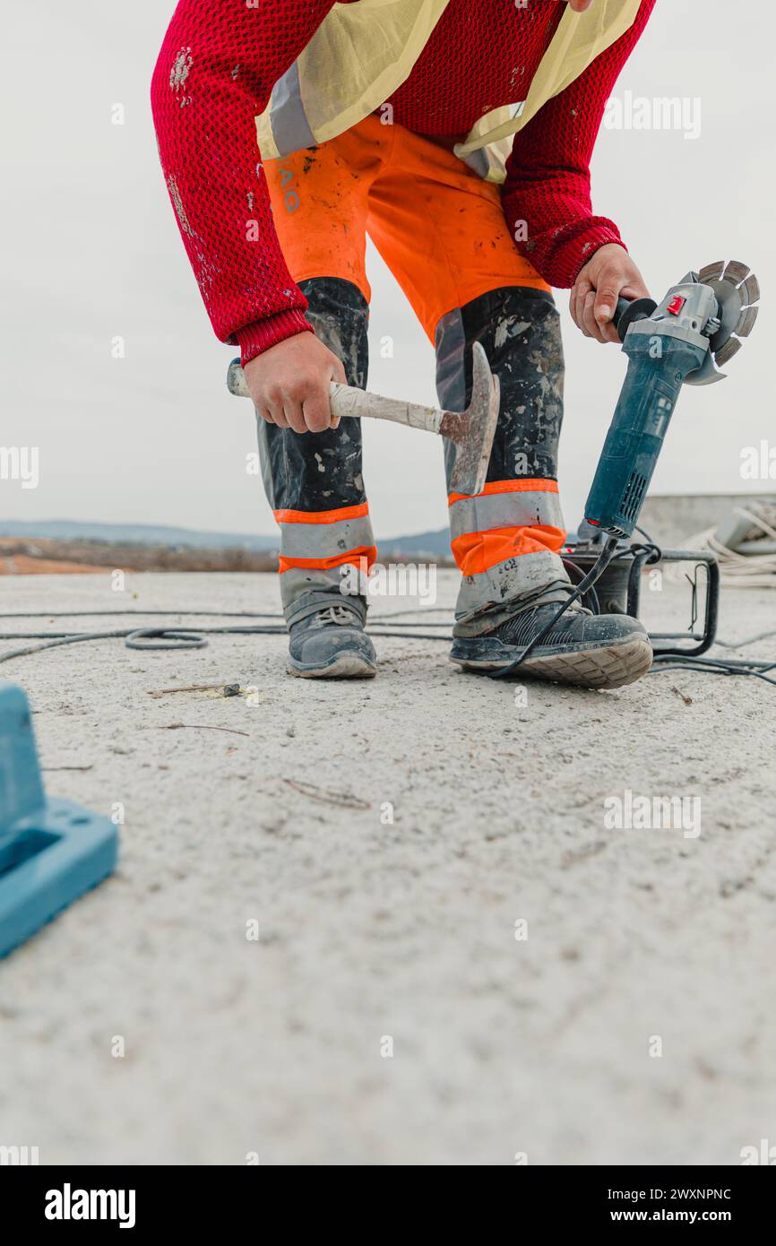 Un operatore elettrico tiene una betoniera su un pavimento di cemento Foto Stock