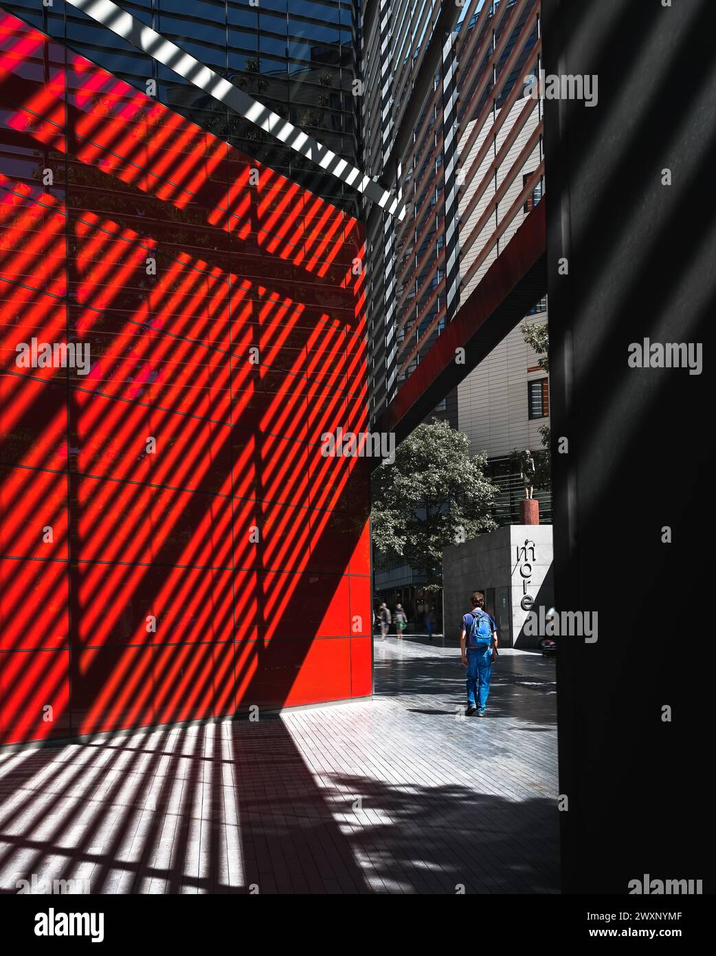 Londra - 18 luglio 2020 - Street Photography of Man Walking Next to Shadow Patterns and Red Wall, Londra Regno Unito Foto Stock