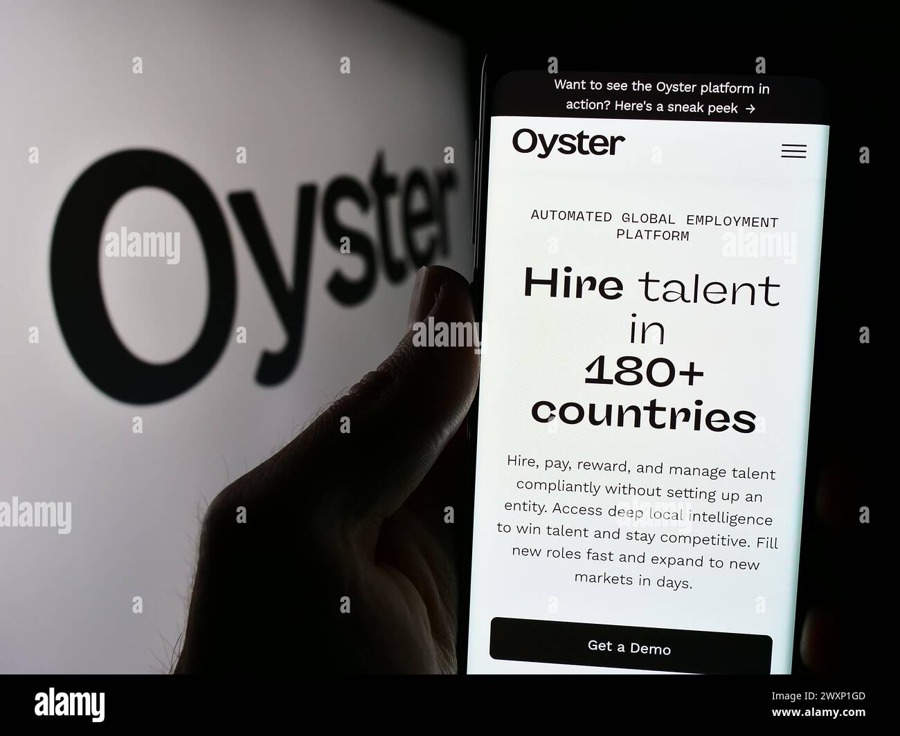 Persona che detiene un cellulare con la pagina Web della società statunitense Oyster HR Inc. Di fronte al logo. Messa a fuoco al centro del display del telefono. Foto Stock