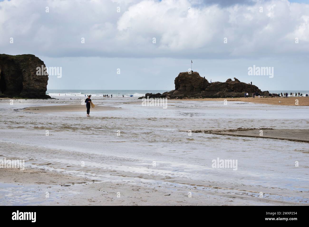 Surfista che cammina dall'oceano a Perranporth, sulla costa nord della Cornovaglia Foto Stock