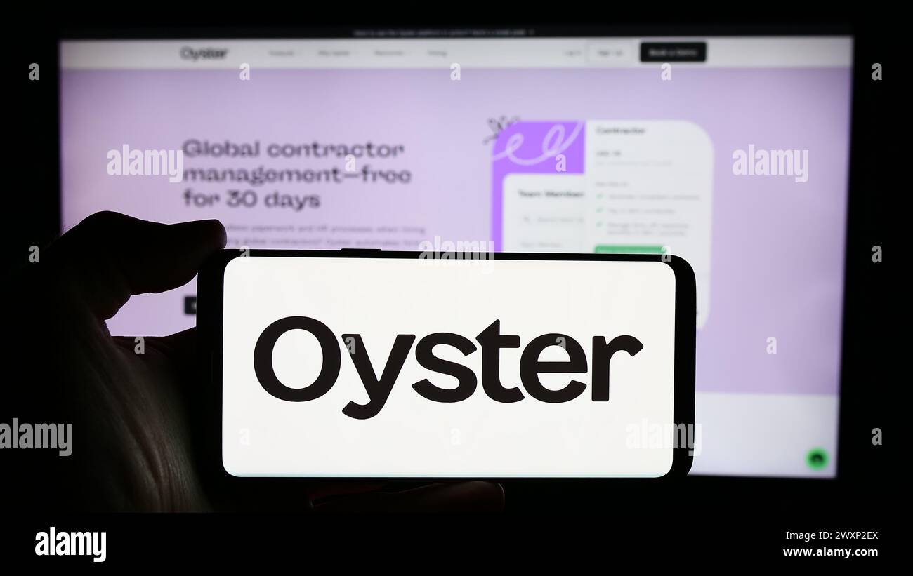 Persona che detiene un cellulare con il logo della società statunitense Oyster HR Inc. Di fronte alla pagina Web aziendale. Mettere a fuoco il display del telefono. Foto Stock