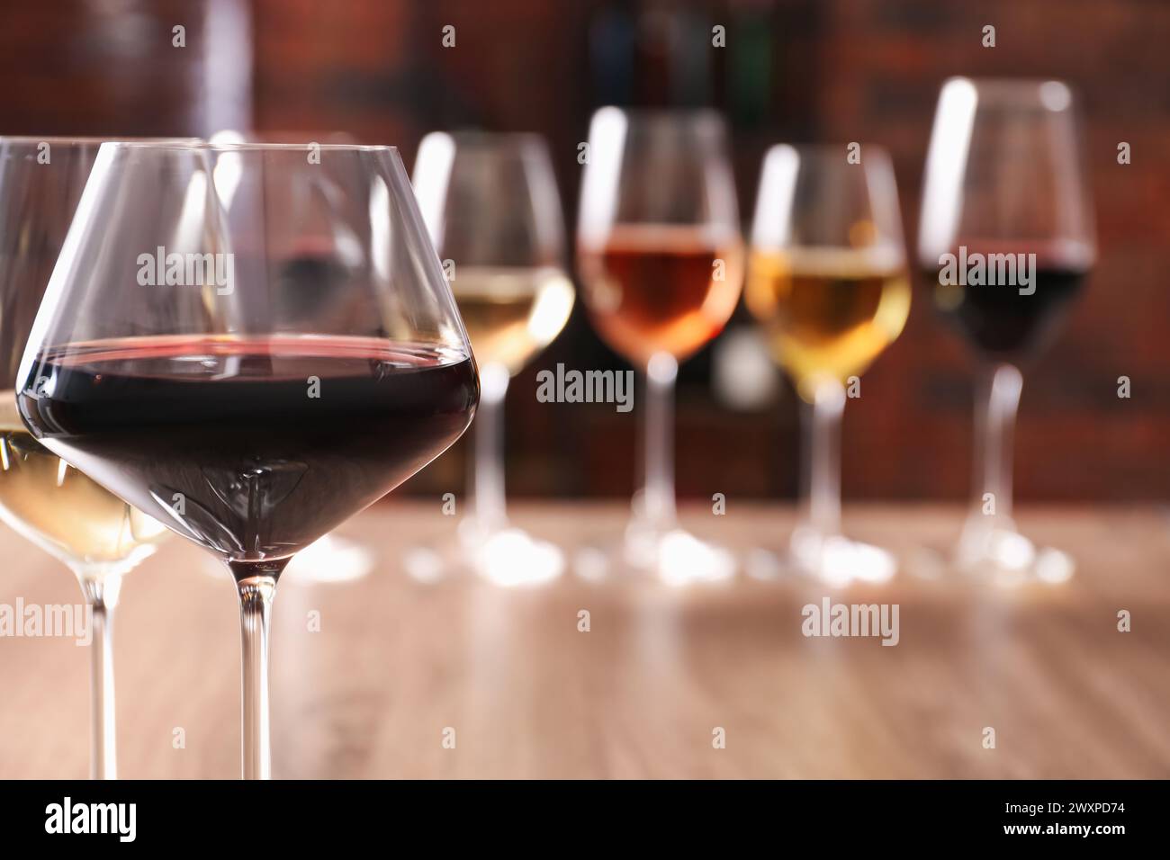 Gustosi vini rossi e bianchi in bicchieri su sfondo sfocato, spazio per testo Foto Stock