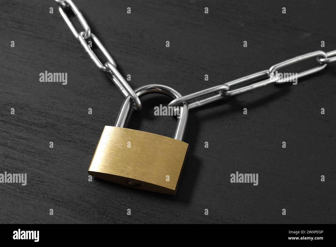 Lucchetto in acciaio con catena su tavolo in legno nero, primo piano Foto Stock