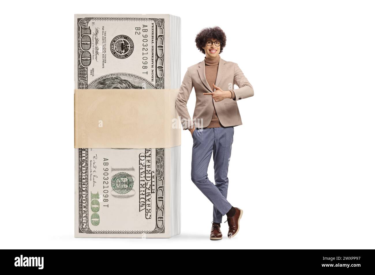 Giovane uomo appoggiato su una pila di soldi e puntando isolato su sfondo bianco Foto Stock