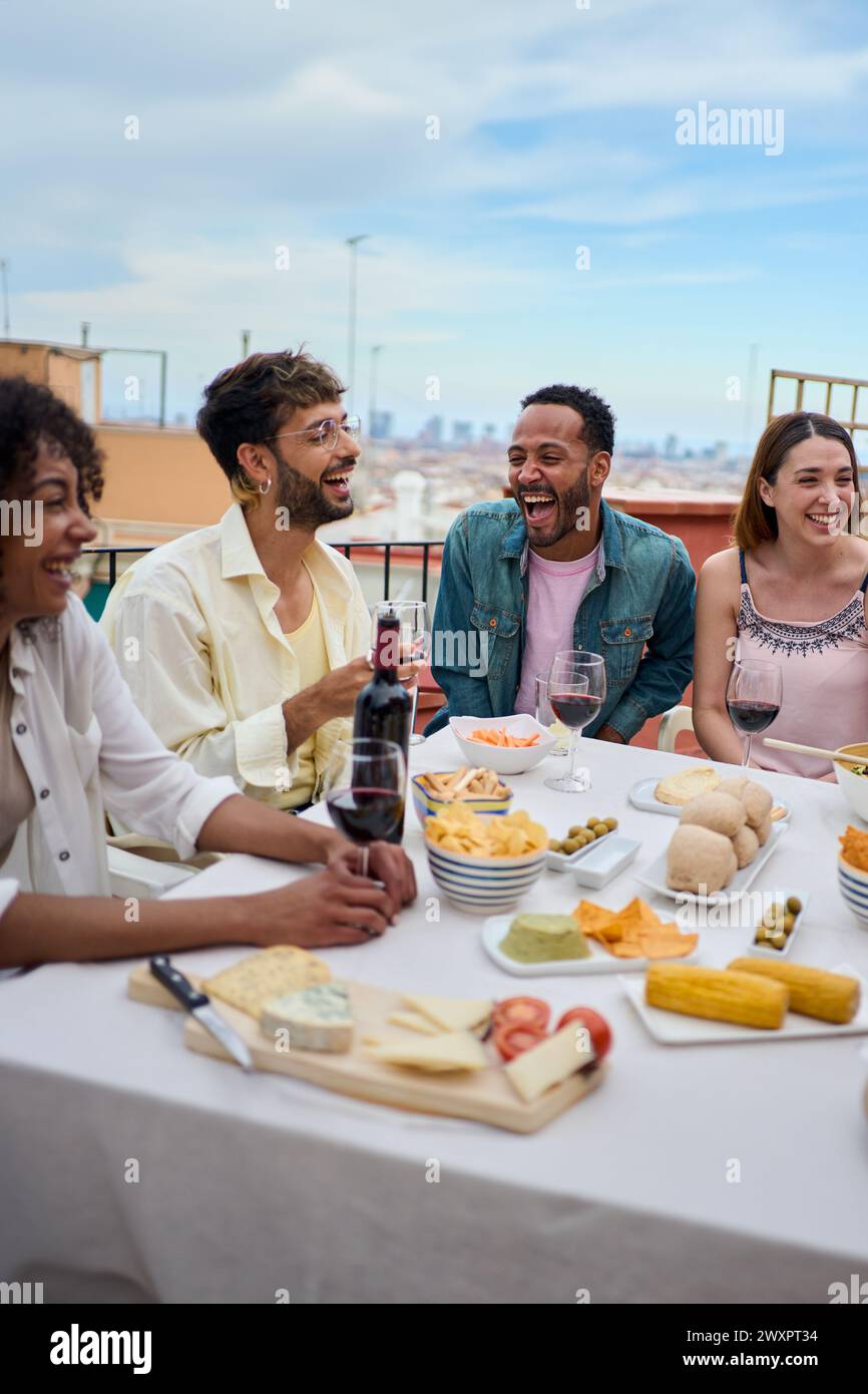 Un gruppo di giovani amici multirazziali che si divertono a pranzare insieme all'aperto. Gente allegra che fa festa. Foto Stock